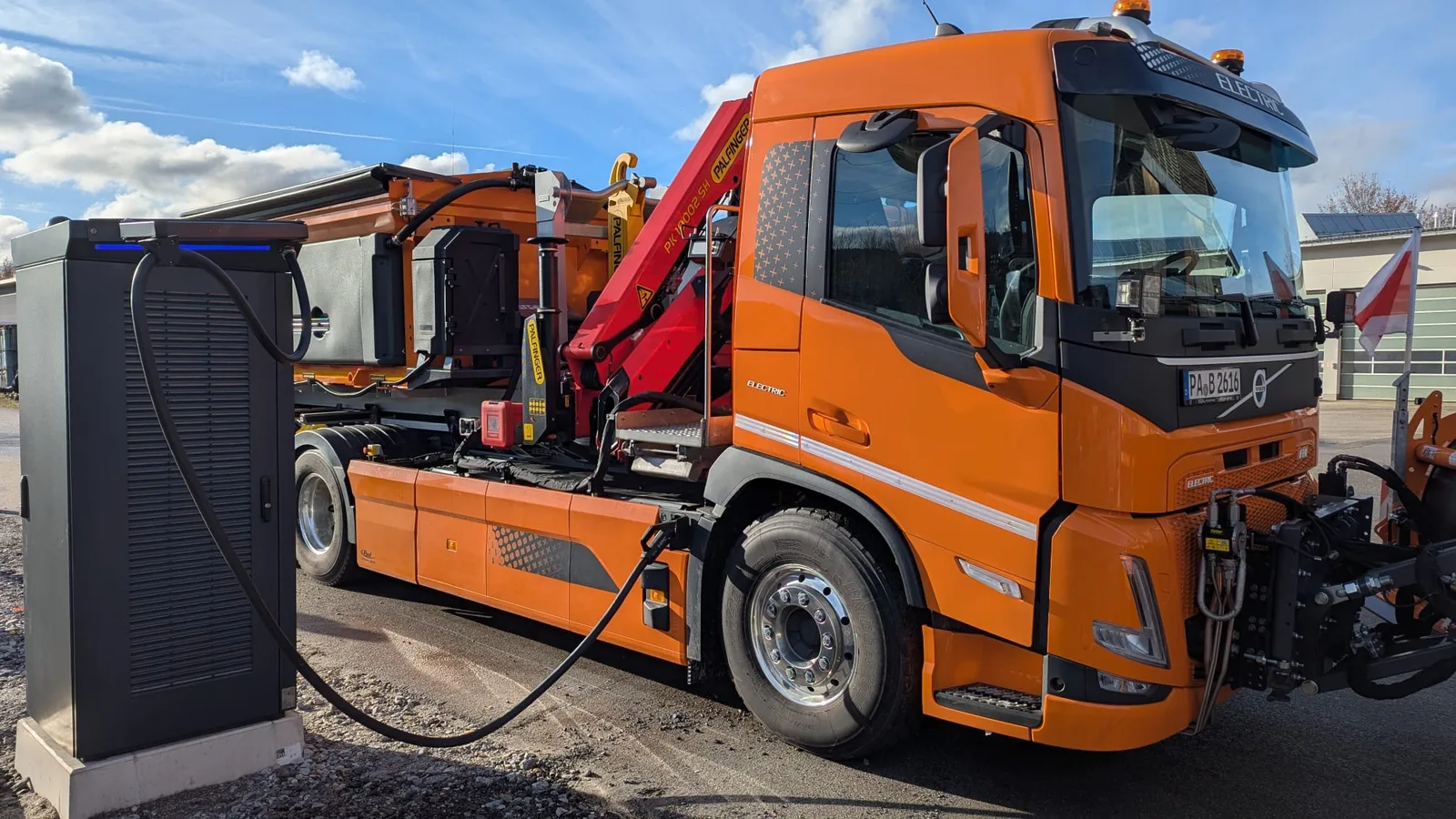 Elektro-LKW lädt an einer DC-Ladestation im ZPAS-Sondergehäuse auf einem Betriebshof