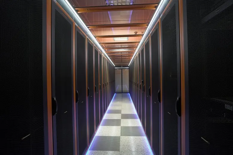 Beleuchtete Gasse zwischen zwei Serverschrankreihen im Carrier-Rechenzentrum